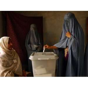  An Afghan Woman Wearing a Burqa Casts Her Ballot at a 